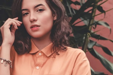 A smiling woman wearing orange clothes promoting apparel.